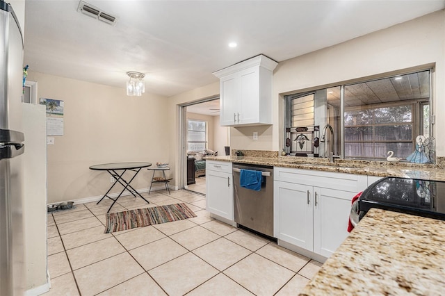 kitchen with light tile patterned floors, visible vents, stainless steel dishwasher, white cabinetry, and a sink