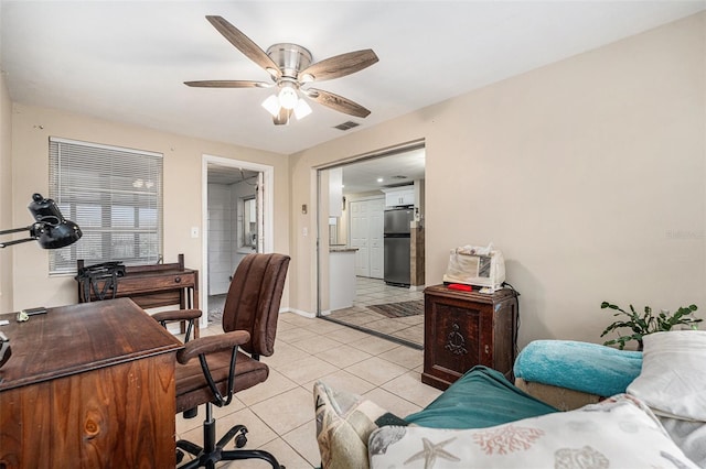 home office with light tile patterned floors, ceiling fan, visible vents, and baseboards