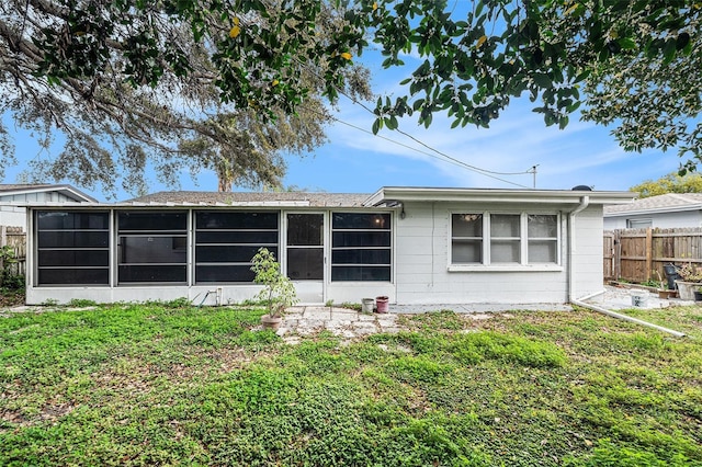 back of house with a yard, fence, and a sunroom