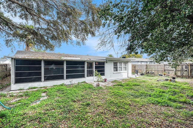 rear view of property featuring a yard, a fenced backyard, and a sunroom