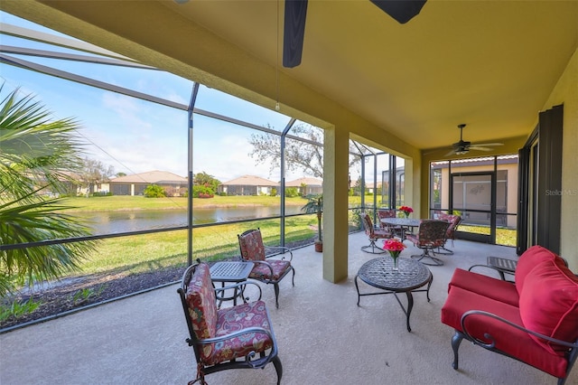 sunroom featuring a ceiling fan and a water view