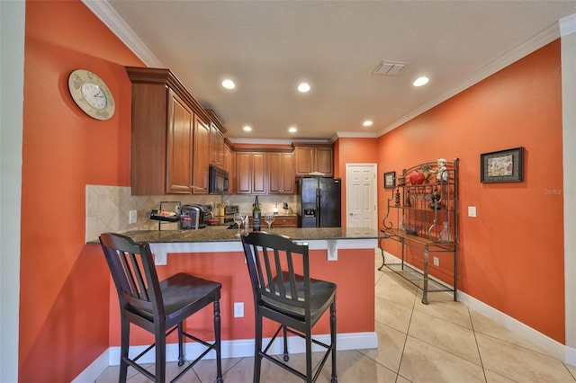 kitchen with a peninsula, visible vents, ornamental molding, brown cabinets, and black appliances