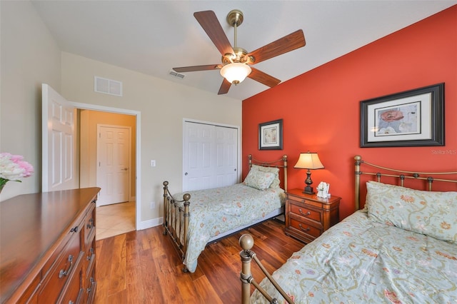 bedroom featuring a closet, wood finished floors, visible vents, and a ceiling fan