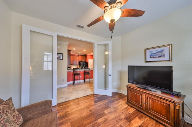 living area with a ceiling fan, visible vents, baseboards, french doors, and light wood finished floors