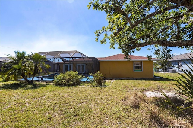 rear view of property featuring an outdoor pool, a lawn, a lanai, fence, and stucco siding