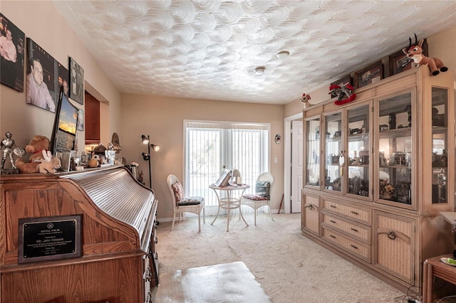 sitting room with baseboards and light colored carpet