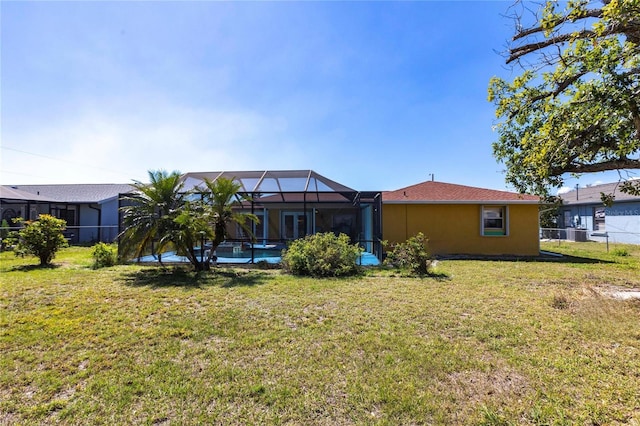 rear view of house with an outdoor pool, a lawn, glass enclosure, fence, and stucco siding