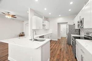 kitchen featuring open shelves, appliances with stainless steel finishes, white cabinetry, a sink, and a peninsula