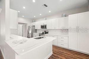 kitchen with light countertops, appliances with stainless steel finishes, a sink, and white cabinets