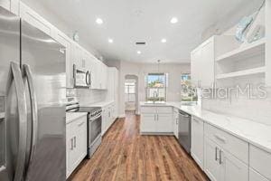 kitchen with a peninsula, appliances with stainless steel finishes, and white cabinets