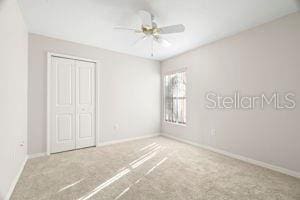 unfurnished bedroom with carpet floors, a closet, a ceiling fan, and baseboards