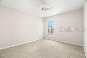 carpeted spare room with a ceiling fan and baseboards