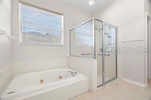 bathroom featuring a jetted tub, a shower stall, and tile patterned floors