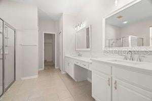 bathroom with tile patterned flooring, a sink, a shower stall, and double vanity