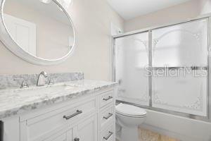 bathroom with vanity, toilet, and bath / shower combo with glass door