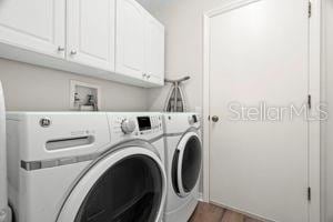 laundry room with washing machine and dryer, cabinet space, and wood finished floors