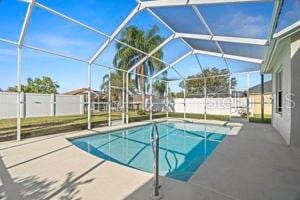 view of pool featuring glass enclosure, a patio, fence, and a fenced in pool