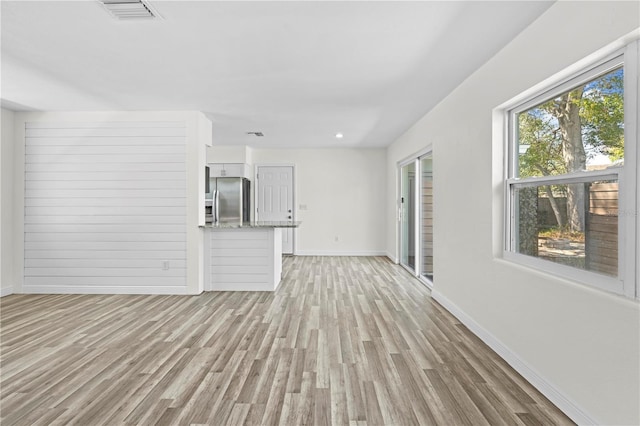 unfurnished living room featuring light wood finished floors, baseboards, and visible vents