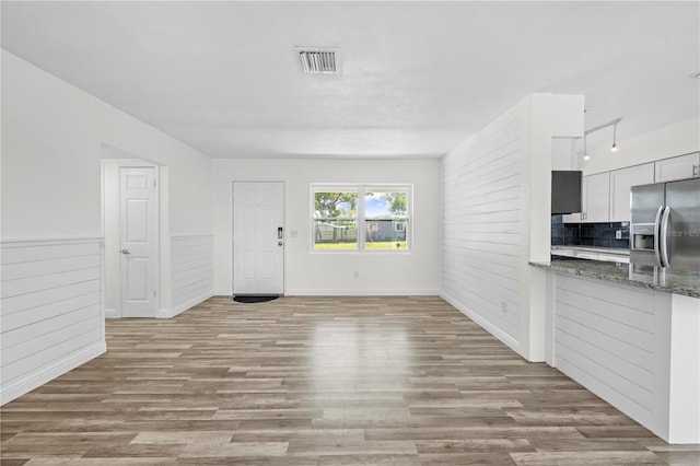 interior space with wainscoting, visible vents, wood walls, and wood finished floors