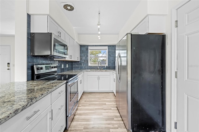 kitchen featuring a sink, visible vents, appliances with stainless steel finishes, decorative backsplash, and light stone countertops