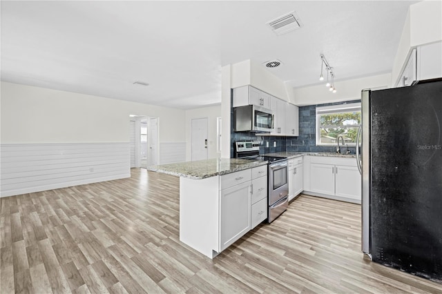 kitchen with light wood-style flooring, visible vents, stainless steel appliances, and light stone counters