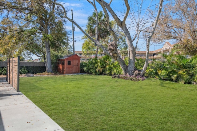 view of yard featuring an outbuilding, fence, and a storage shed