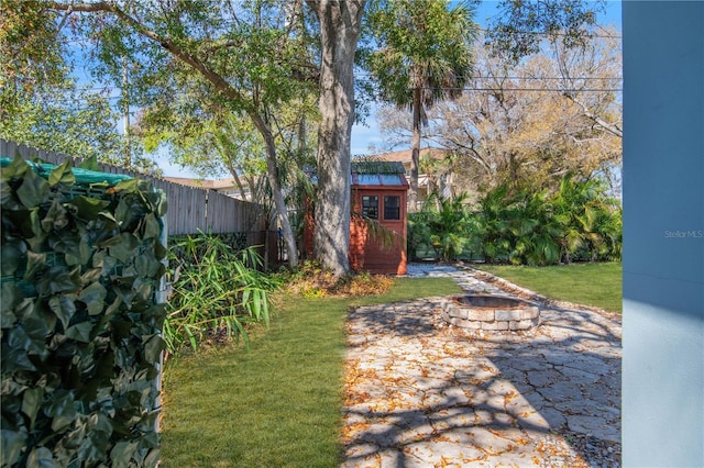 view of yard featuring an outdoor fire pit, fence, and an outdoor structure