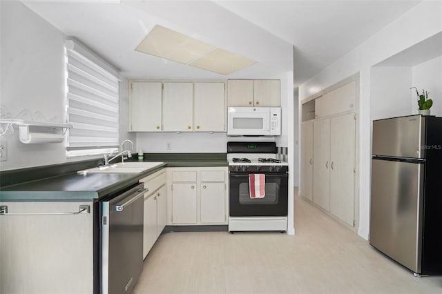 kitchen featuring appliances with stainless steel finishes, dark countertops, and a sink