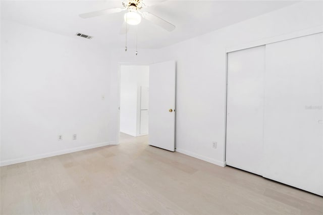 unfurnished bedroom with light wood-style flooring, a closet, visible vents, and baseboards