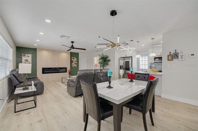 dining area with recessed lighting, a large fireplace, visible vents, baseboards, and light wood-style floors