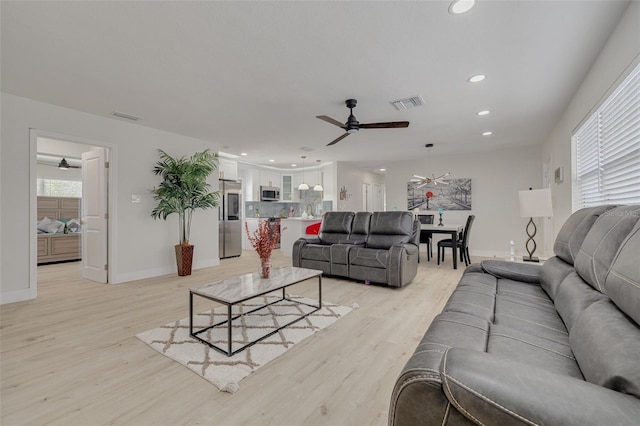 living area with light wood-style flooring, visible vents, baseboards, and recessed lighting