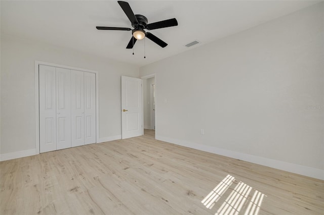 unfurnished bedroom featuring baseboards, a closet, visible vents, and wood finished floors