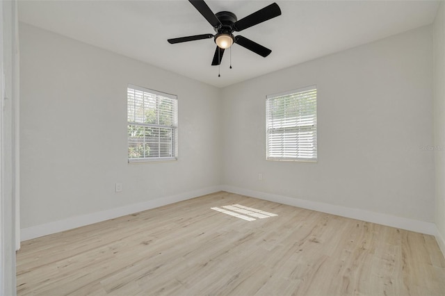 spare room featuring a ceiling fan, wood finished floors, a wealth of natural light, and baseboards