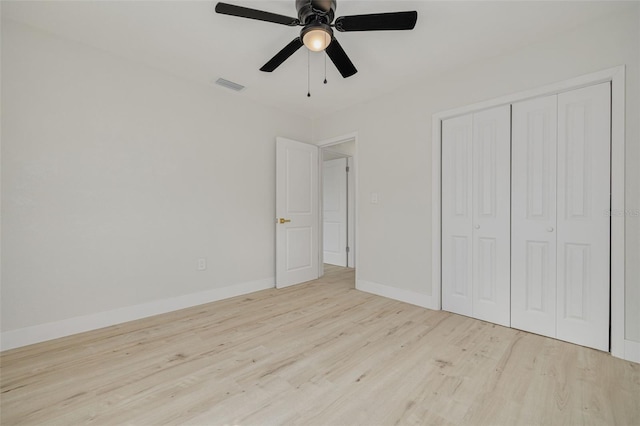 unfurnished bedroom featuring ceiling fan, wood finished floors, visible vents, baseboards, and a closet