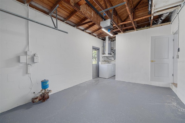 garage with washing machine and dryer, concrete block wall, and a garage door opener