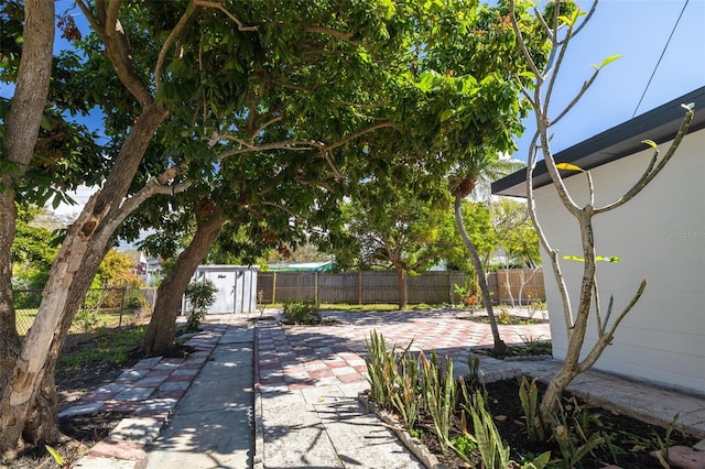 view of patio with an outbuilding, a fenced backyard, and a storage unit