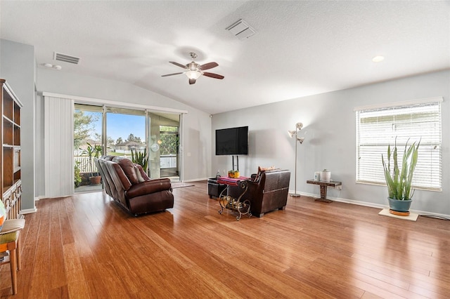 living room with a wealth of natural light, visible vents, and hardwood / wood-style floors