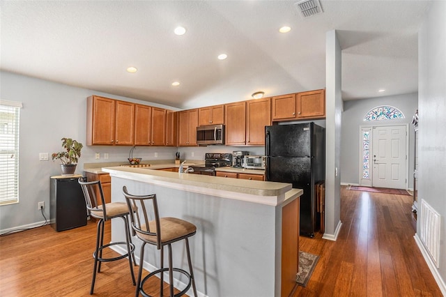 kitchen featuring light countertops, visible vents, an island with sink, and black appliances