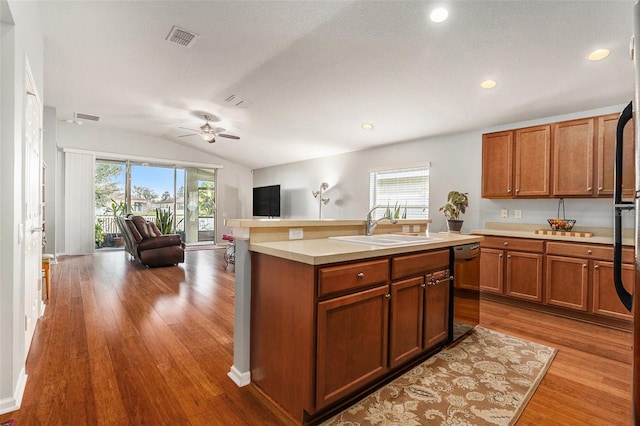 kitchen featuring visible vents, dishwasher, lofted ceiling, open floor plan, and light countertops