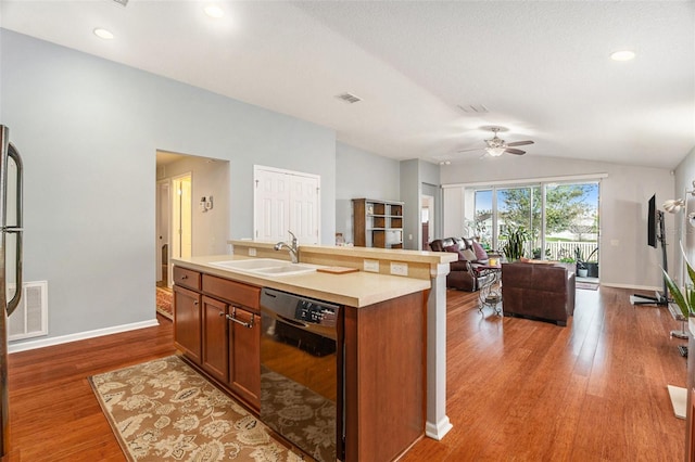 kitchen featuring visible vents, dishwasher, wood finished floors, vaulted ceiling, and a sink