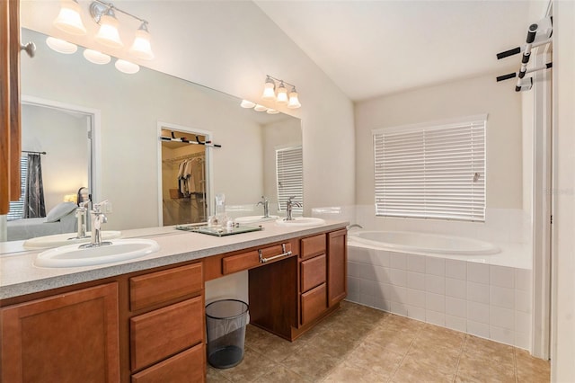 bathroom featuring tile patterned flooring, a sink, vaulted ceiling, a bath, and double vanity