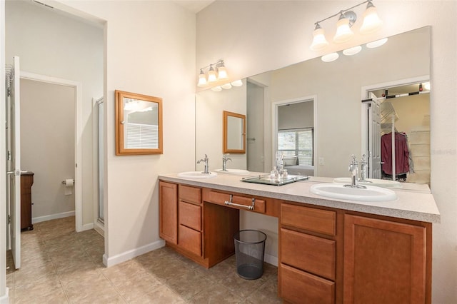 full bath featuring double vanity, baseboards, and a sink