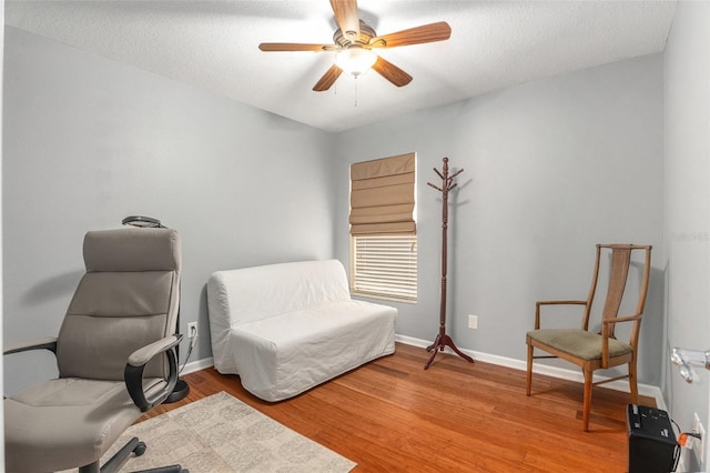 home office featuring light wood-style flooring, baseboards, ceiling fan, and a textured ceiling