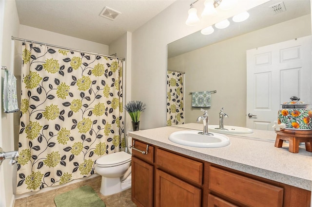 bathroom featuring toilet, vanity, visible vents, and tile patterned floors