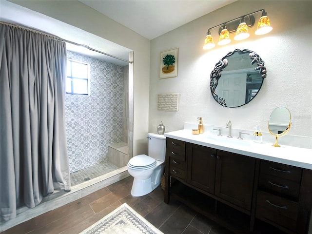 full bathroom with toilet, wood finish floors, tiled shower, and vanity