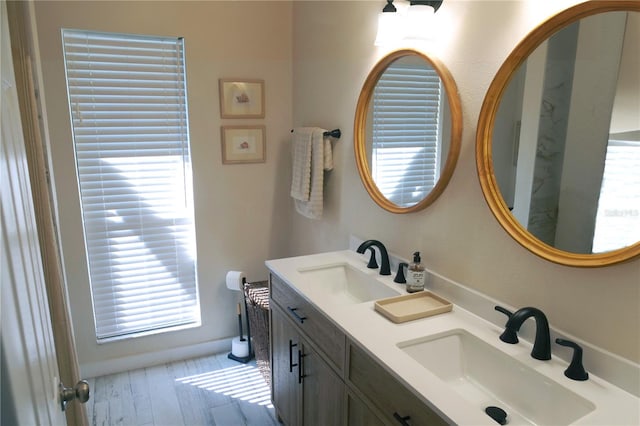 full bathroom featuring double vanity, wood finished floors, and a sink