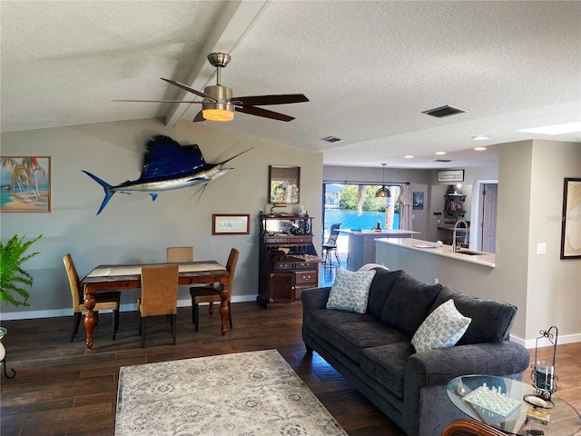 living area featuring a textured ceiling, lofted ceiling with beams, wood finished floors, visible vents, and baseboards