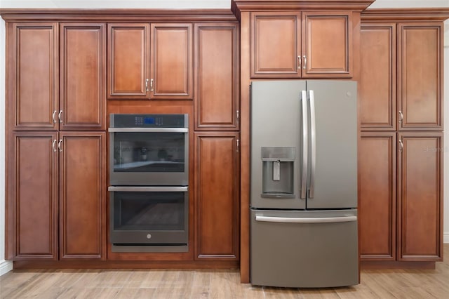 kitchen with stainless steel appliances, light wood-style flooring, and brown cabinets