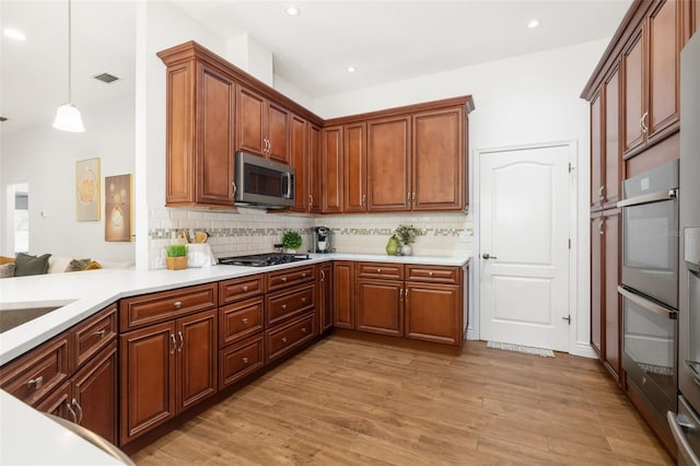 kitchen with light wood finished floors, visible vents, stainless steel microwave, and tasteful backsplash