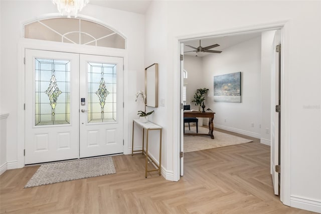 foyer with ceiling fan with notable chandelier, french doors, and baseboards